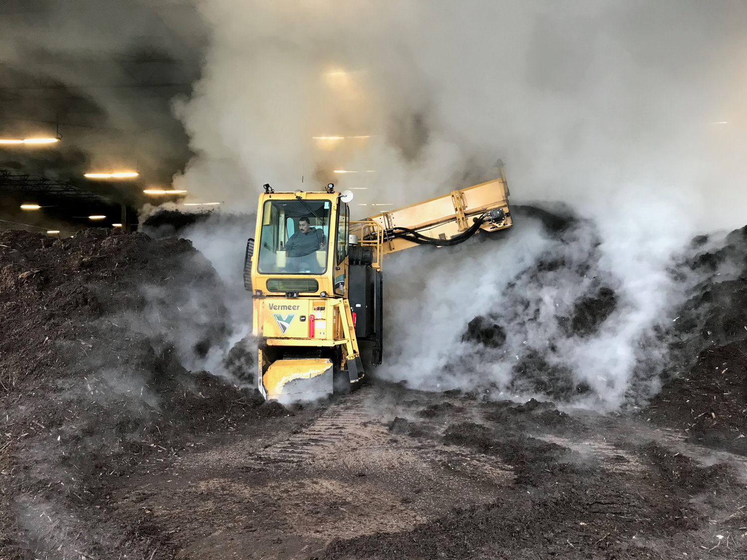 At Silver Springs Organics in Rainier, Armondo Lugo drives a machine that turns over giant steaming piles of compost.